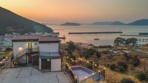 A hotel with a pool, a staircase, and a view of the sea and mountains. - Geoje Piscina Pool Villa (Geoje)
