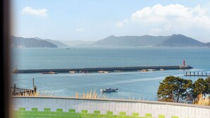 A coastal view with a pier extending into the water, boats, and distant mountains. - Geoje Piscina Pool Villa (Geoje)