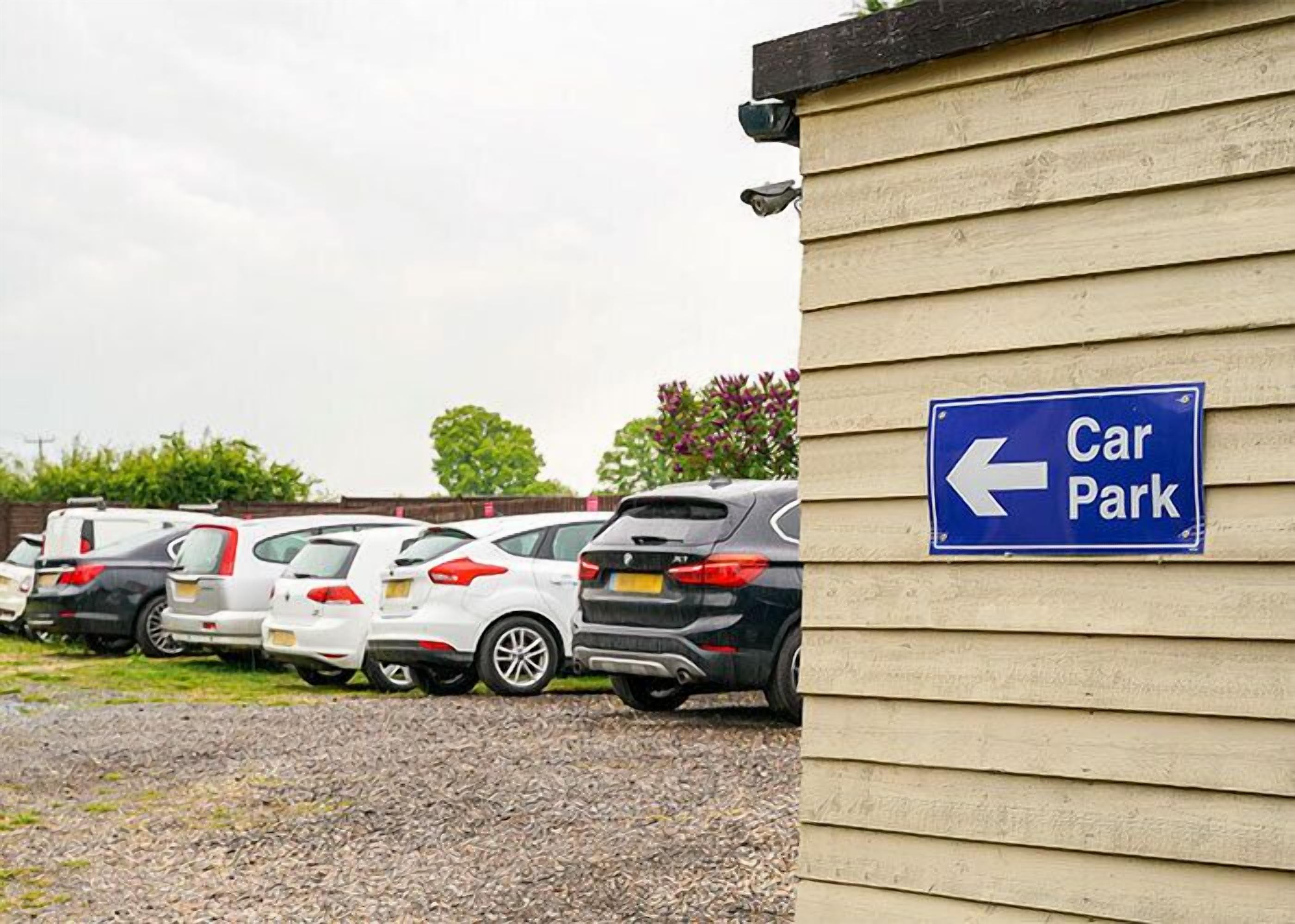 A car park with a blue sign indicating the direction to the parking area.