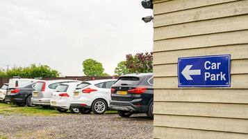 A car park with a blue sign indicating the direction to the parking area.