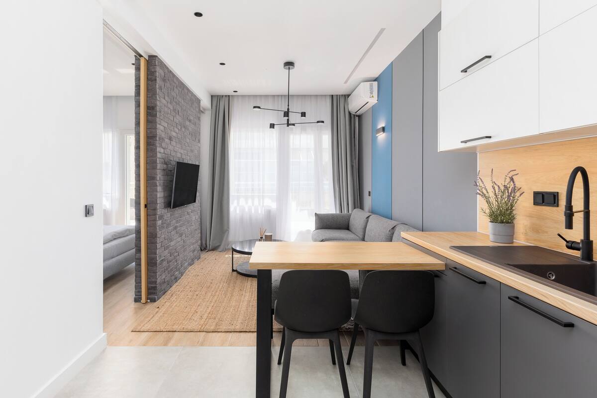 A modern kitchen with a wooden countertop, black chairs, and a built-in sink.