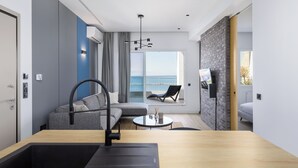 Ein modernes Wohnzimmer mit einer Couch, einem Esstisch und Blick auf das Meer.