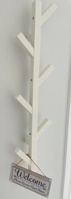 A white wall-mounted coat rack with a 'Welcome' sign below it.