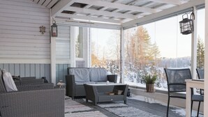 Een overdekt terras met een bank, stoelen en een tafel.