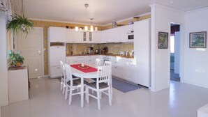 Een moderne keuken met witte kasten, een eettafel met stoelen en een hangplant.