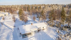 Een besneeerd landschap met een huis met een glazen gevel en een sneeuwbedekte dak.