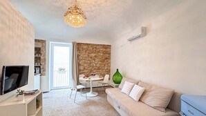 Uma sala de estar com sofá, televisão, mesa de jantar e parede de pedra.