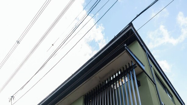 A building with a green facade, vertical blinds on the windows, and a banner with Japanese characters. - KYOTO INN MIO (Kyoto)