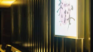 A reception area with a modern design, featuring a wall-mounted sign with Chinese characters and a series of black cylindrical objects on a ledge. - KYOTO INN MIO (Kyoto)