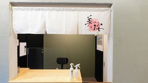 A room with a wooden table, two spray bottles, and a white curtain with a pink design. - KYOTO INN MIO (Kyoto)