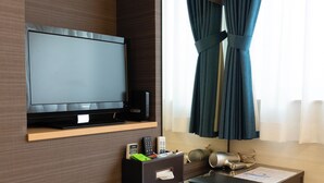 A hotel room with a flat-screen TV, a desk with a telephone, a kettle, and two mugs, a small ottoman, and a window with curtains. - KYOTO INN MIO (Kyoto)