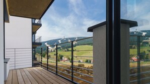 Un balcon offrant une vue sur un paysage rural, avec des champs et une colline au loin.