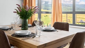A dining table set with plates, glasses, and cutlery, with a vase of flowers in the center. - Beautiful apartment for 5 people with WIFI, TV and balcony (Klášterec Nad Ohrí)