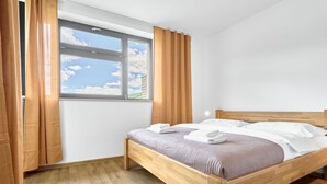 A bedroom with a wooden bed, white bedding, and a window with curtains. - Beautiful apartment for 5 people with WIFI, TV and balcony (Klášterec Nad Ohrí)