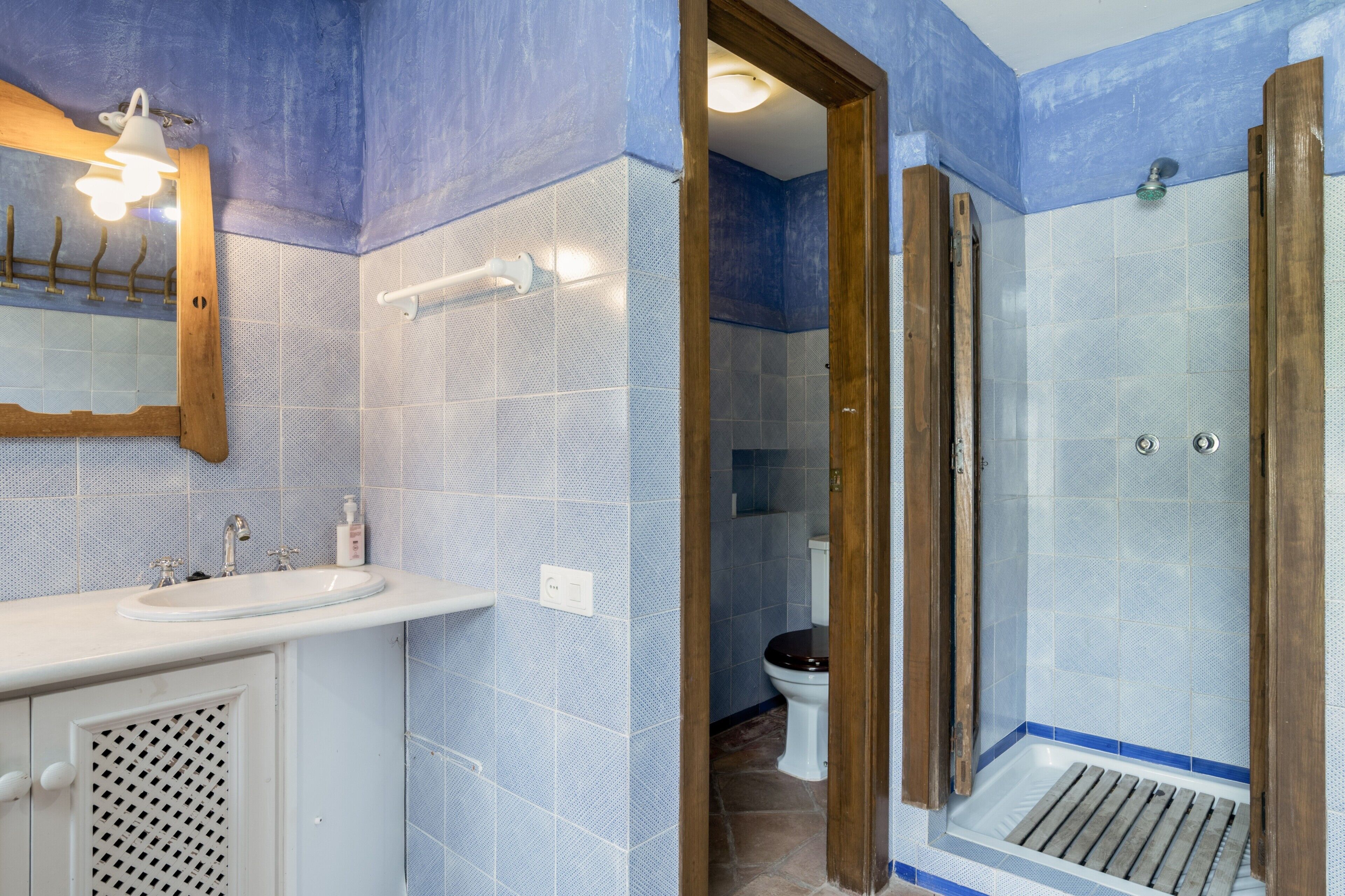 A bathroom with a sink, mirror, shower, and toilet.