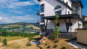 A modern two-story building with a balcony, a view of a town in the background, and a clear sky. - Cosy apartment for 6 guests with WIFI, TV and balcony (Klášterec Nad Ohrí)