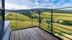 A balcony with a wooden floor and metal railing, overlooking a rural landscape with fields and scattered houses. - Cosy apartment for 6 guests with WIFI, TV and balcony (Klášterec Nad Ohrí)