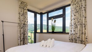A bedroom with a large bed, a window with a view of a forest, and a plant on the windowsill. - Cosy apartment for 6 guests with WIFI, TV and balcony (Klášterec Nad Ohrí)