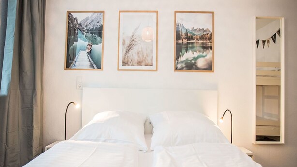 A hotel room with a large bed, a nightstand, and three framed pictures on the wall. - Beautiful apartment for 4 guests with WIFI, TV and balcony (Winterberg)