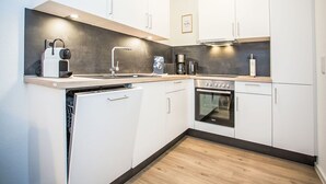 A compact kitchen with white cabinets, a built-in oven, a dishwasher, and a coffee maker. - Beautiful apartment for 4 guests with WIFI, TV and balcony (Winterberg)
