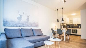 A modern living room with a grey sofa, a small round table, and a painting of deer on the wall. - Beautiful apartment for 4 guests with WIFI, TV and balcony (Winterberg)