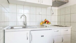 A kitchen with white cabinets, a stainless steel sink, and a fruit bowl on the countertop.
