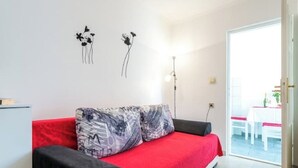 A room with a red sofa, a small table, and a wall with two black floral wall art pieces.
