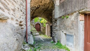 Un stretto sentiero in pietra sotto un arco, che conduce a una porta in legno.