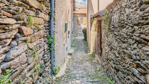 Un stretto vicolo acciottolato tra edifici in pietra, con un cielo sereno sopra.