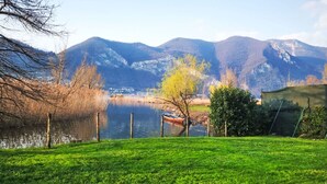 Eine grüne Wiese mit einem Gewässer, Bergen im Hintergrund und einem kleinen Boot.