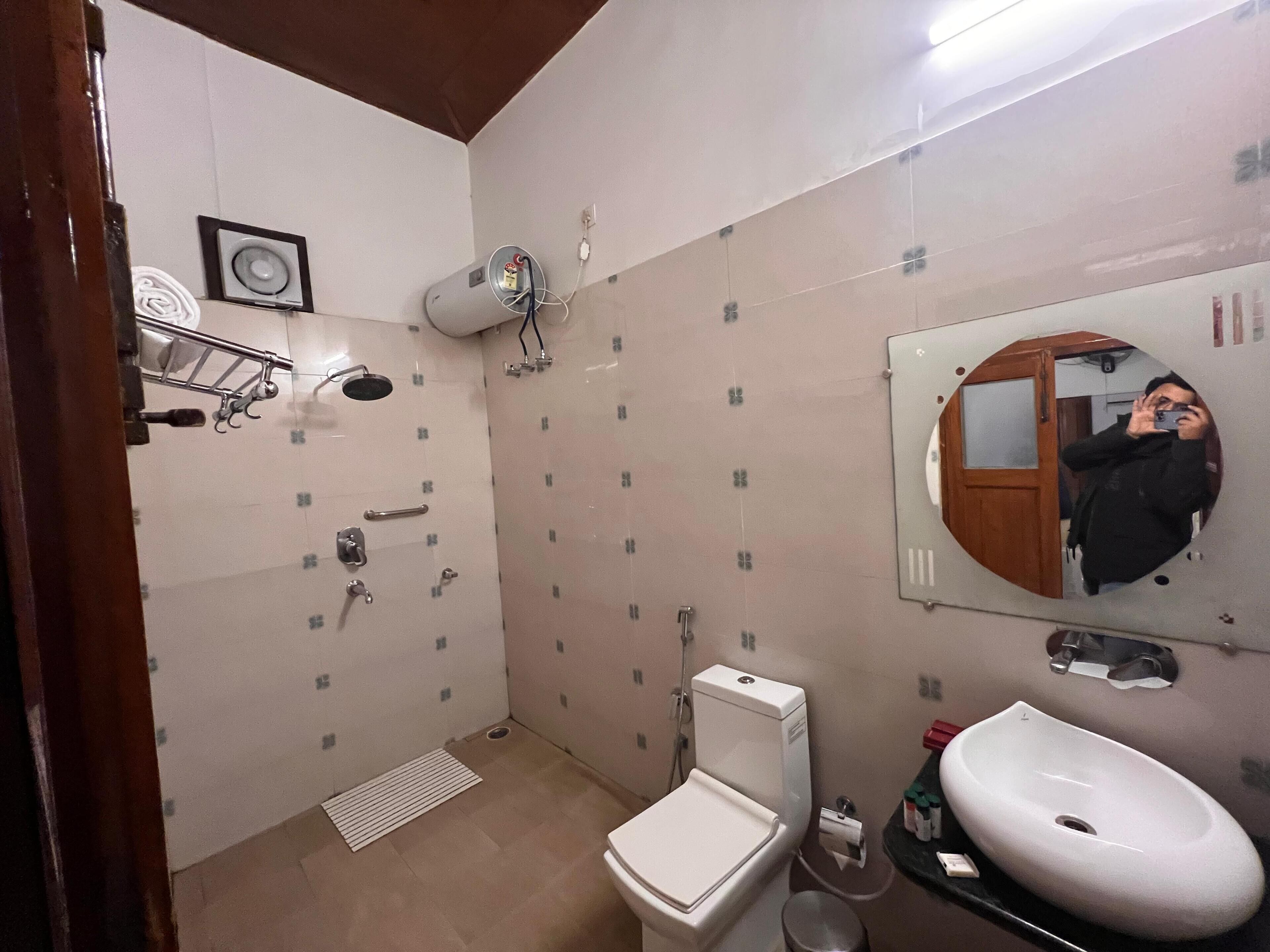 A small bathroom with a toilet, sink, shower, and a mirror.