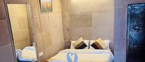 A hotel room with two beds, a large mirror, a wall-mounted air conditioner, and a patterned floor.