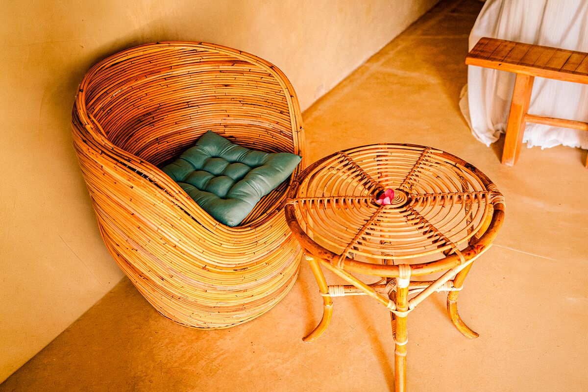 A wicker chair with a cushioned seat and a matching stool.