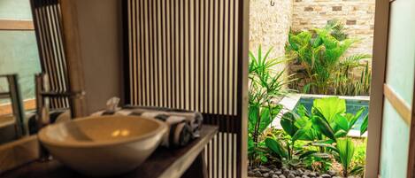 Un baño con un lavabo grande, un espejo y una pared a rayas.