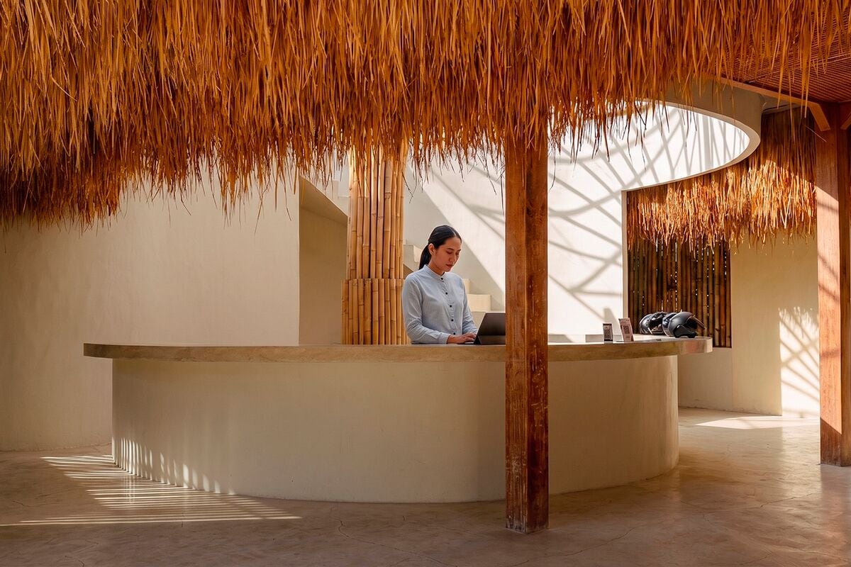 A reception desk with a person behind it, a curved counter, and a ceiling with hanging elements.