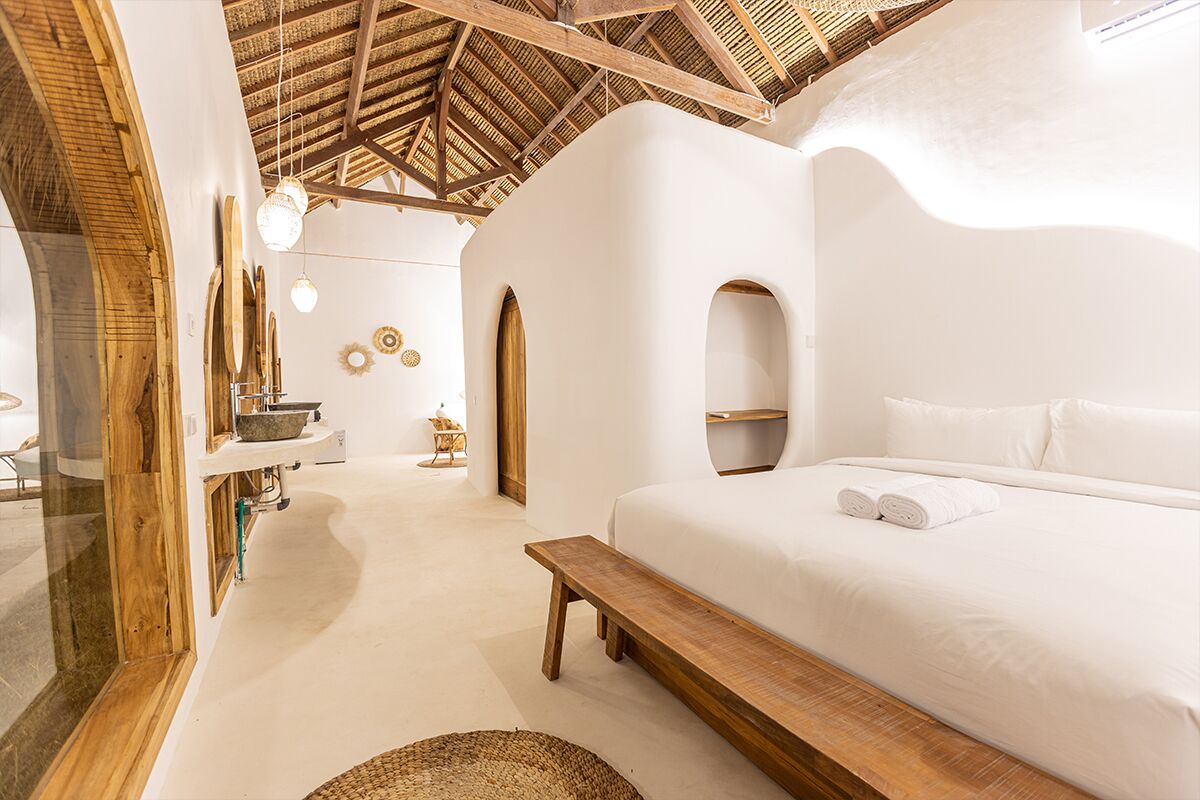 Una habitación con cama, banco y vista a un interior rústico.