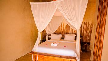 A bed with a canopy, pillows, and a rolled towel on the bed.