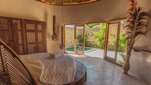 A bedroom with a large bed, a wooden headboard, a large window, and a view of a swimming pool. - Lombok Souls (Senggigi)