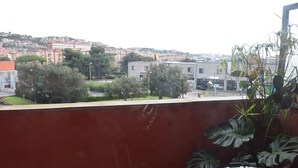 Ein Balkon mit Blick auf eine Stadtansicht, einschließlich Gebäude und Bäume.