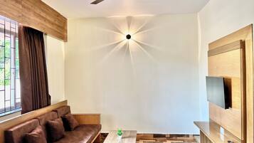 Una sala de estar moderna con un sofá, una mesa de centro, un televisor montado en la pared y un ventilador de techo.
