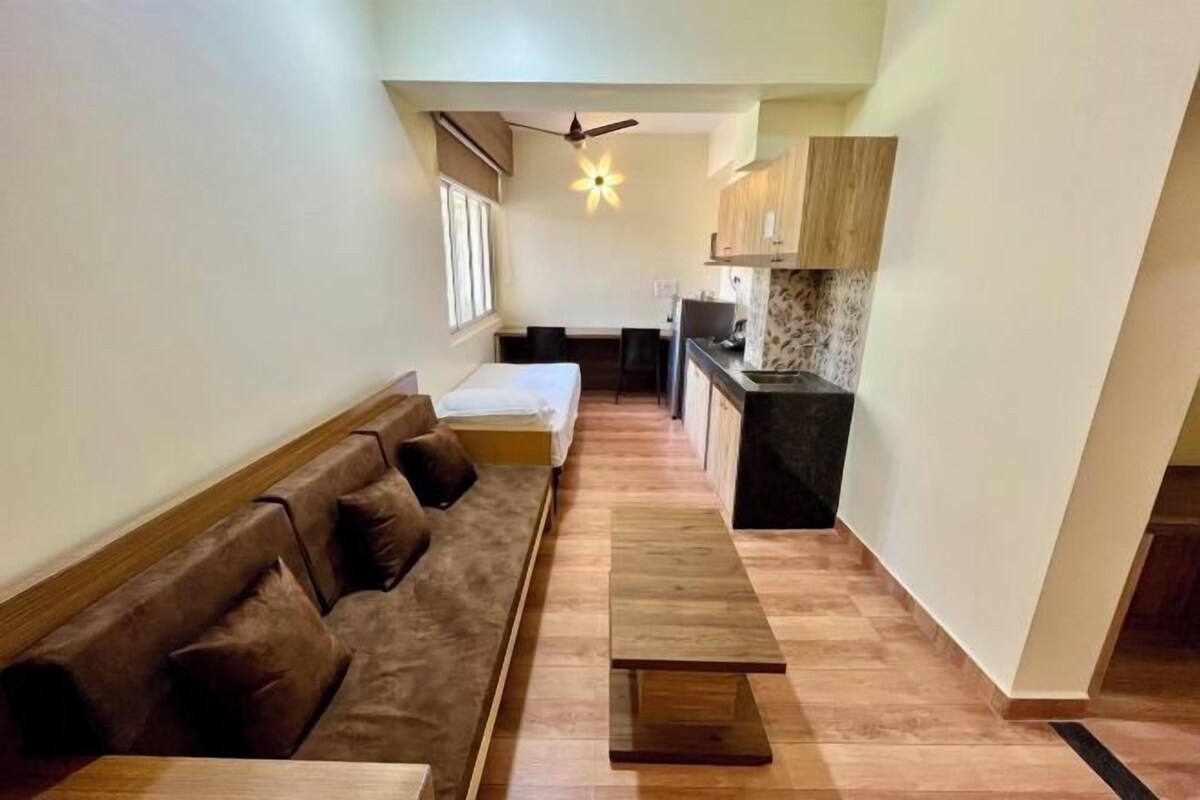 A compact living space with a sofa, a small dining table, a kitchenette, and a ceiling fan.