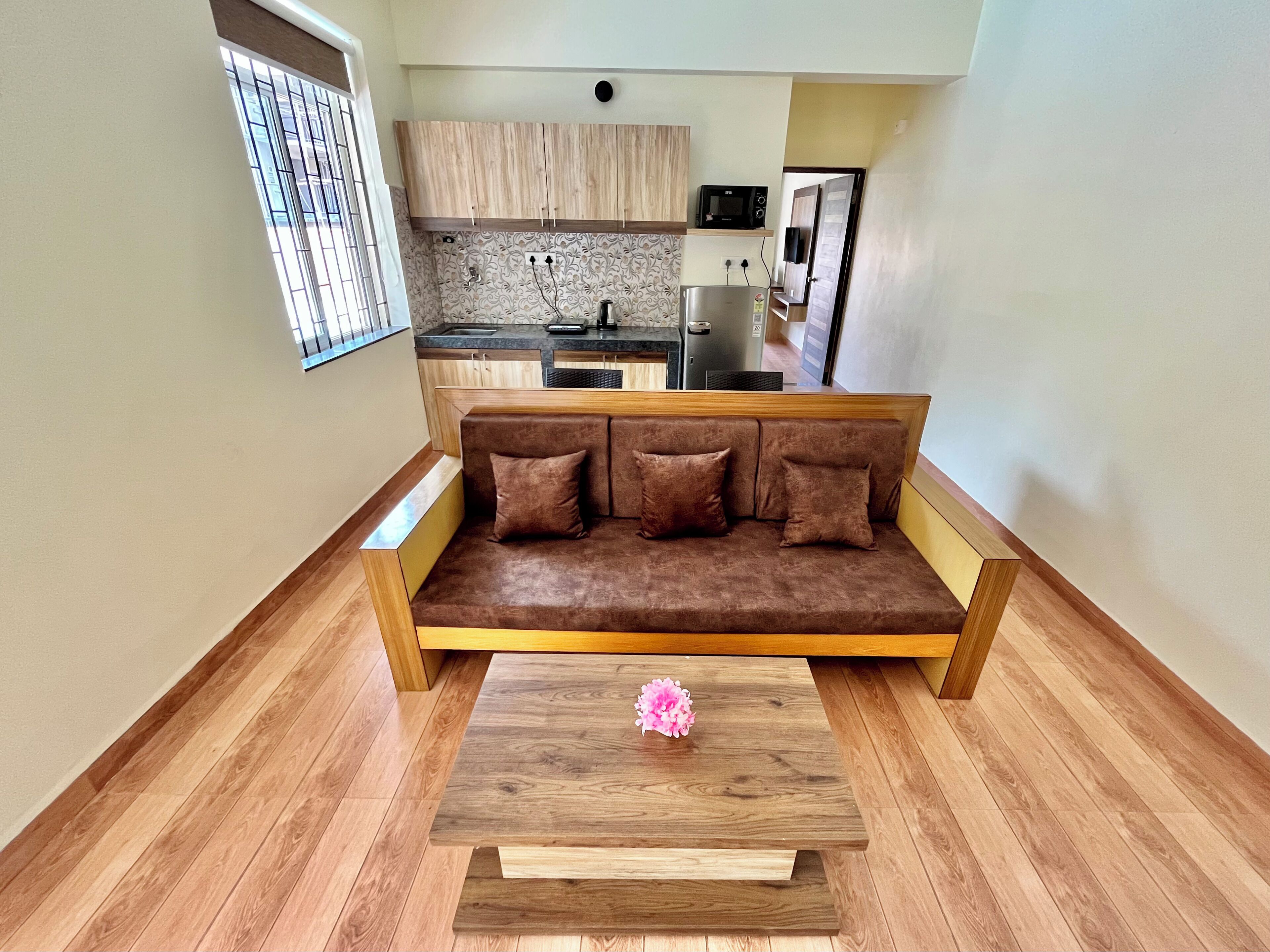 Una sala de estar moderna con un sofá de madera, una mesa de centro y una cocina al fondo.