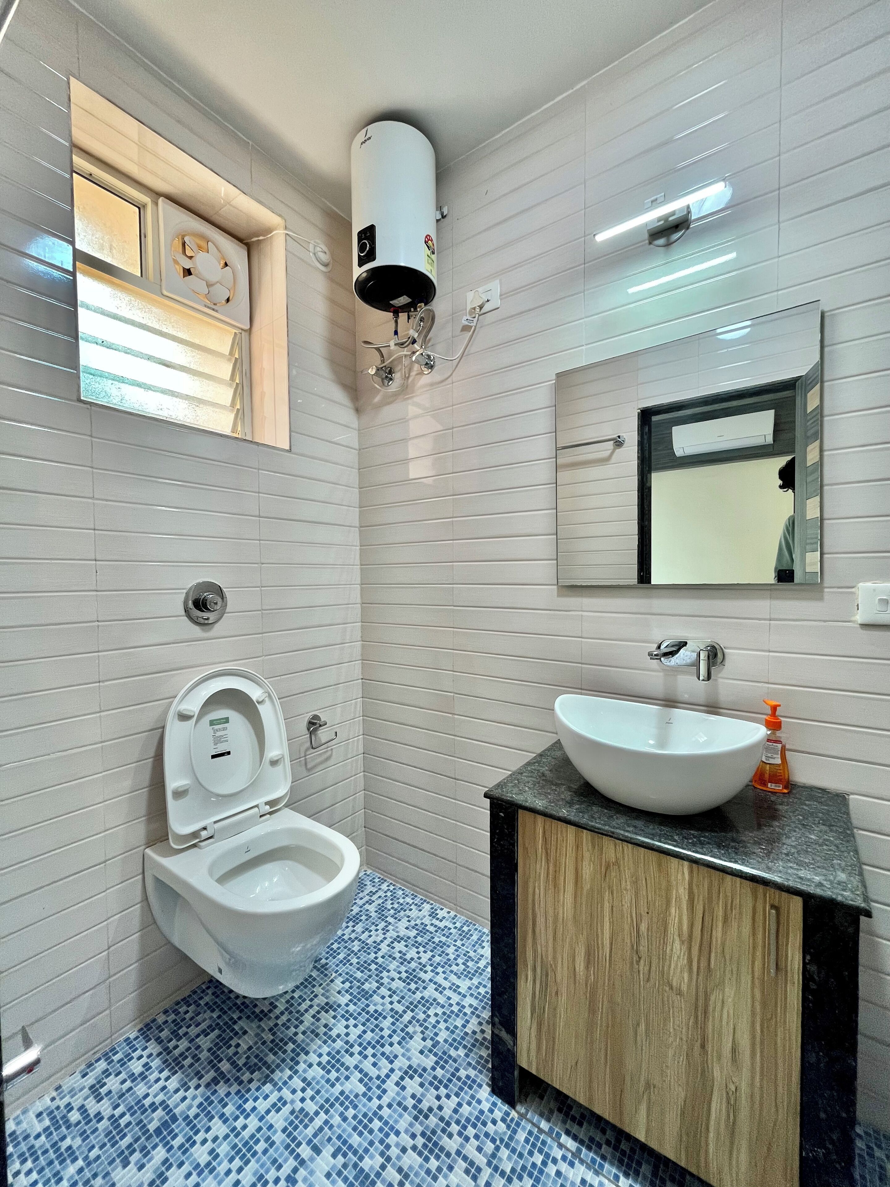 A bathroom with a toilet, sink, and mirror.