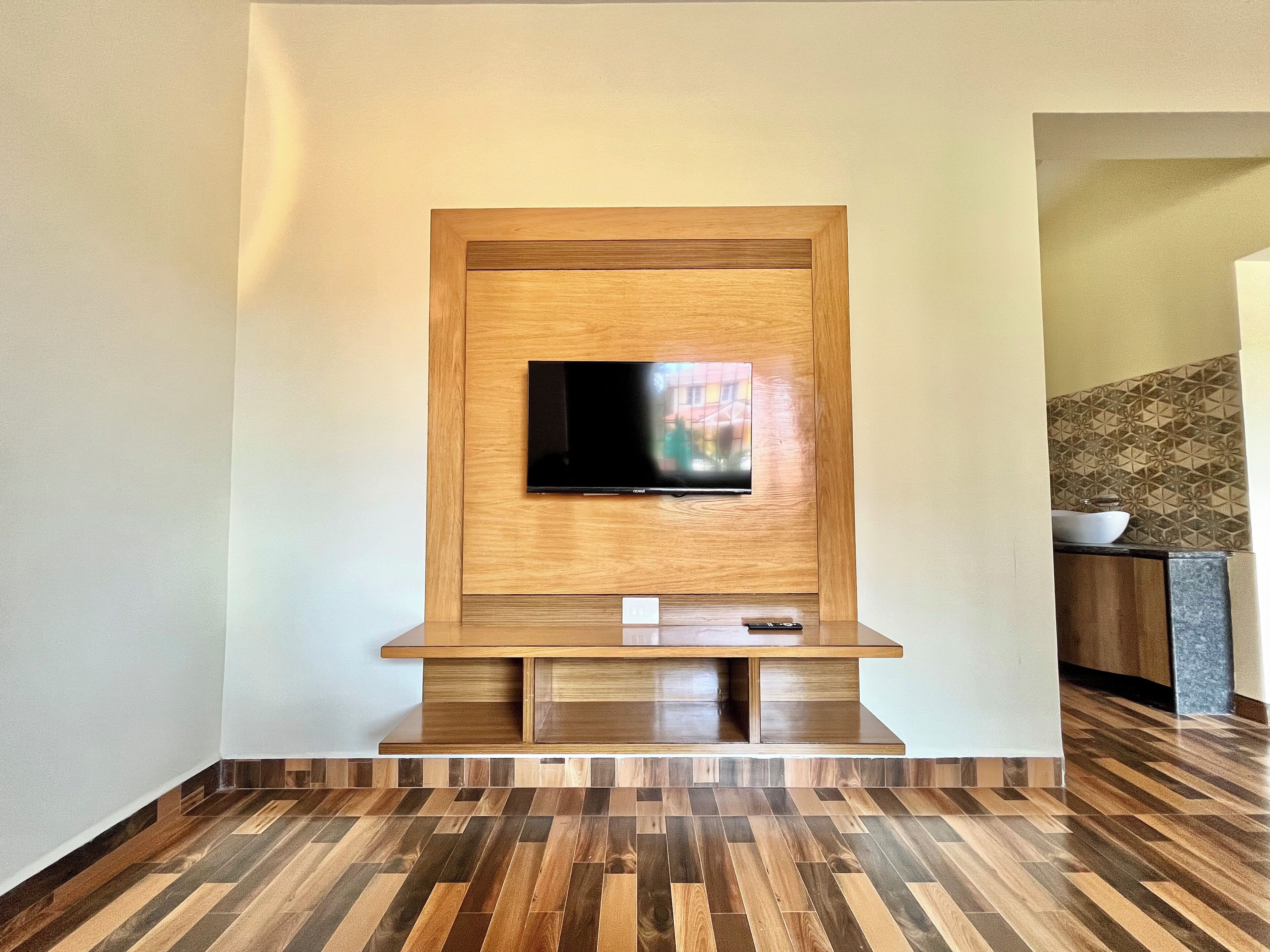 Una sala de estar moderna con un mueble de entretenimiento de madera, un televisor de pantalla plana y un suelo con motivo de espiga.