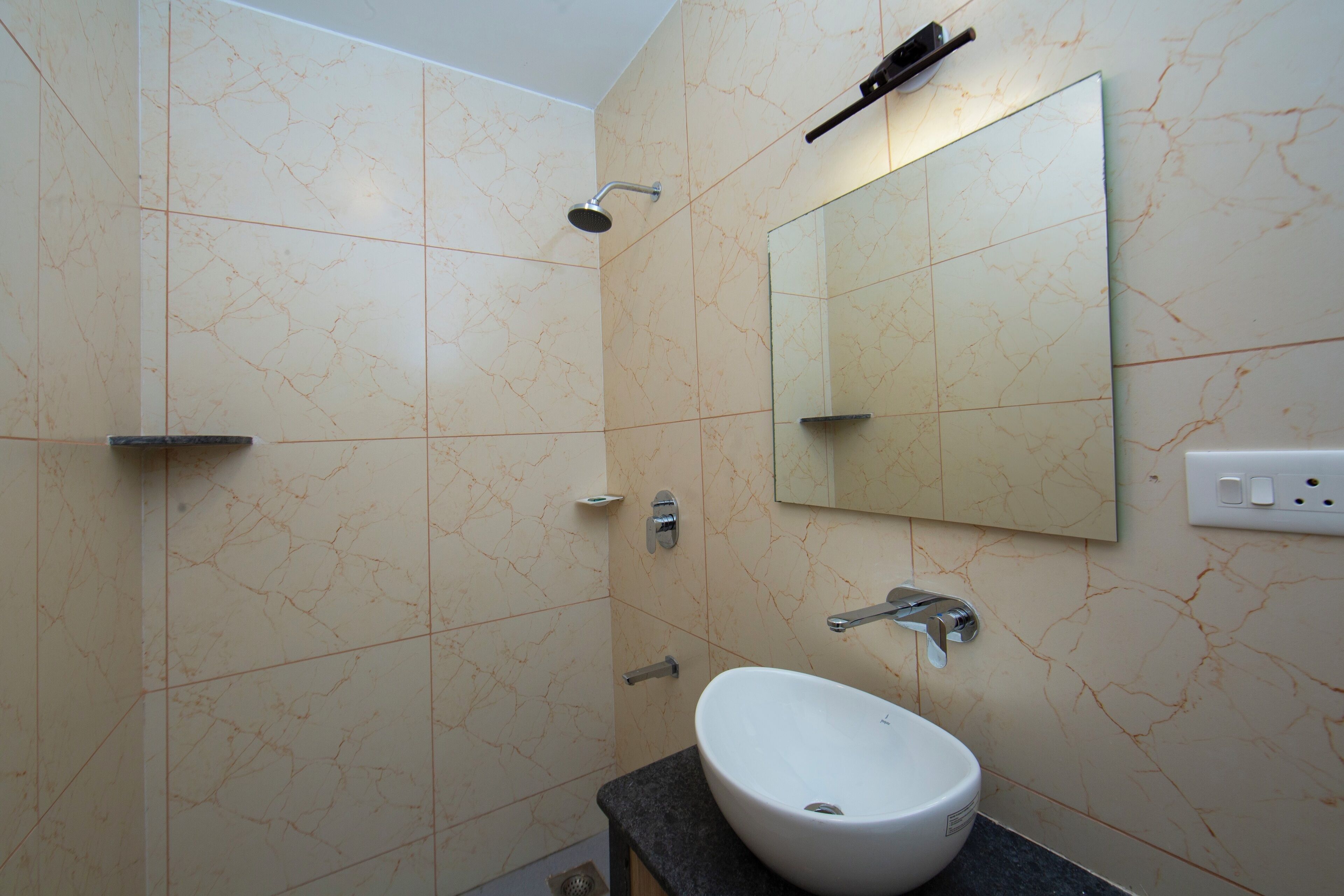 A bathroom with a white sink, a mirror, a showerhead, and a towel rack.