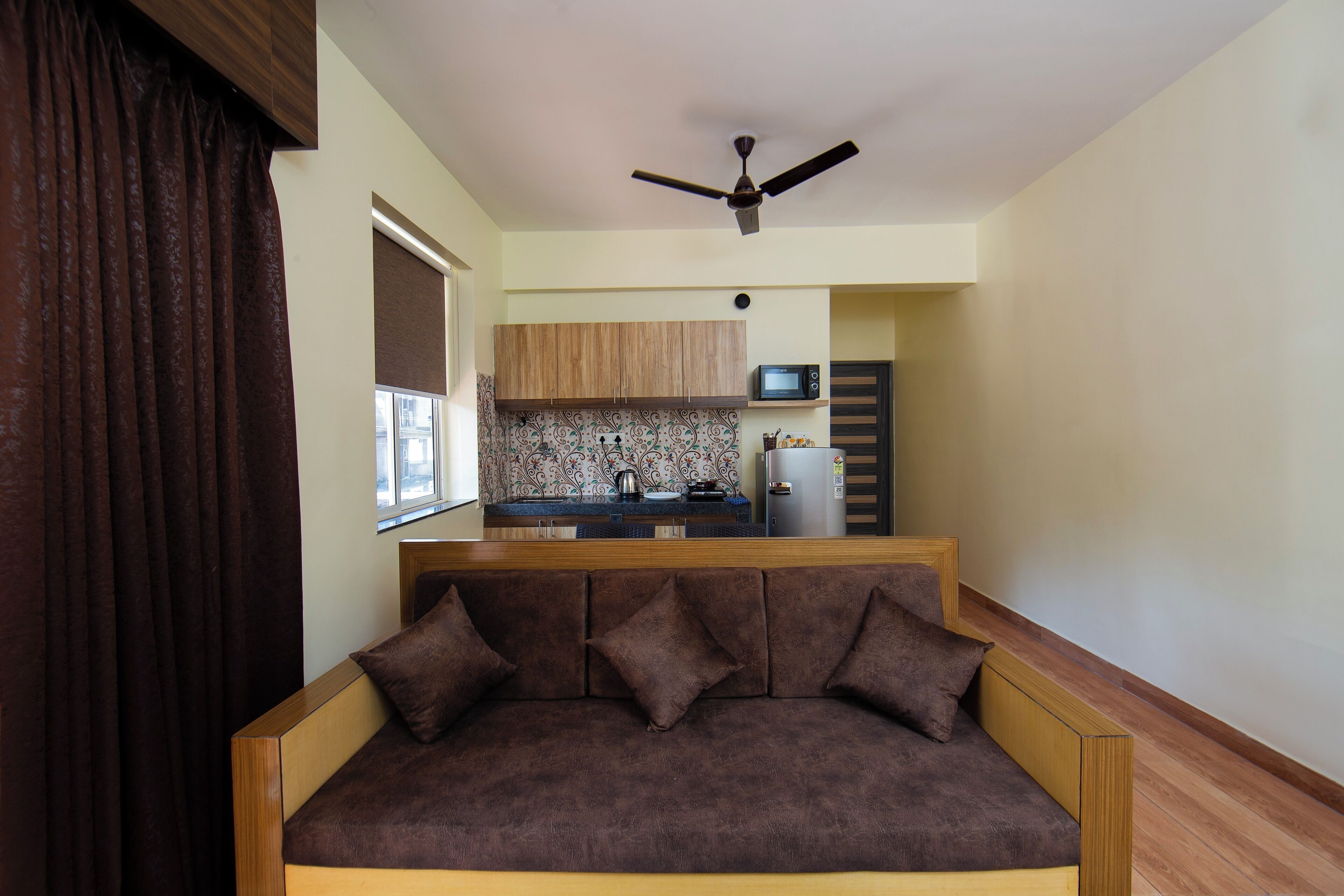 Ein modernes Wohnzimmer mit einer Couch, einem Deckenventilator und einer Küche im Hintergrund.