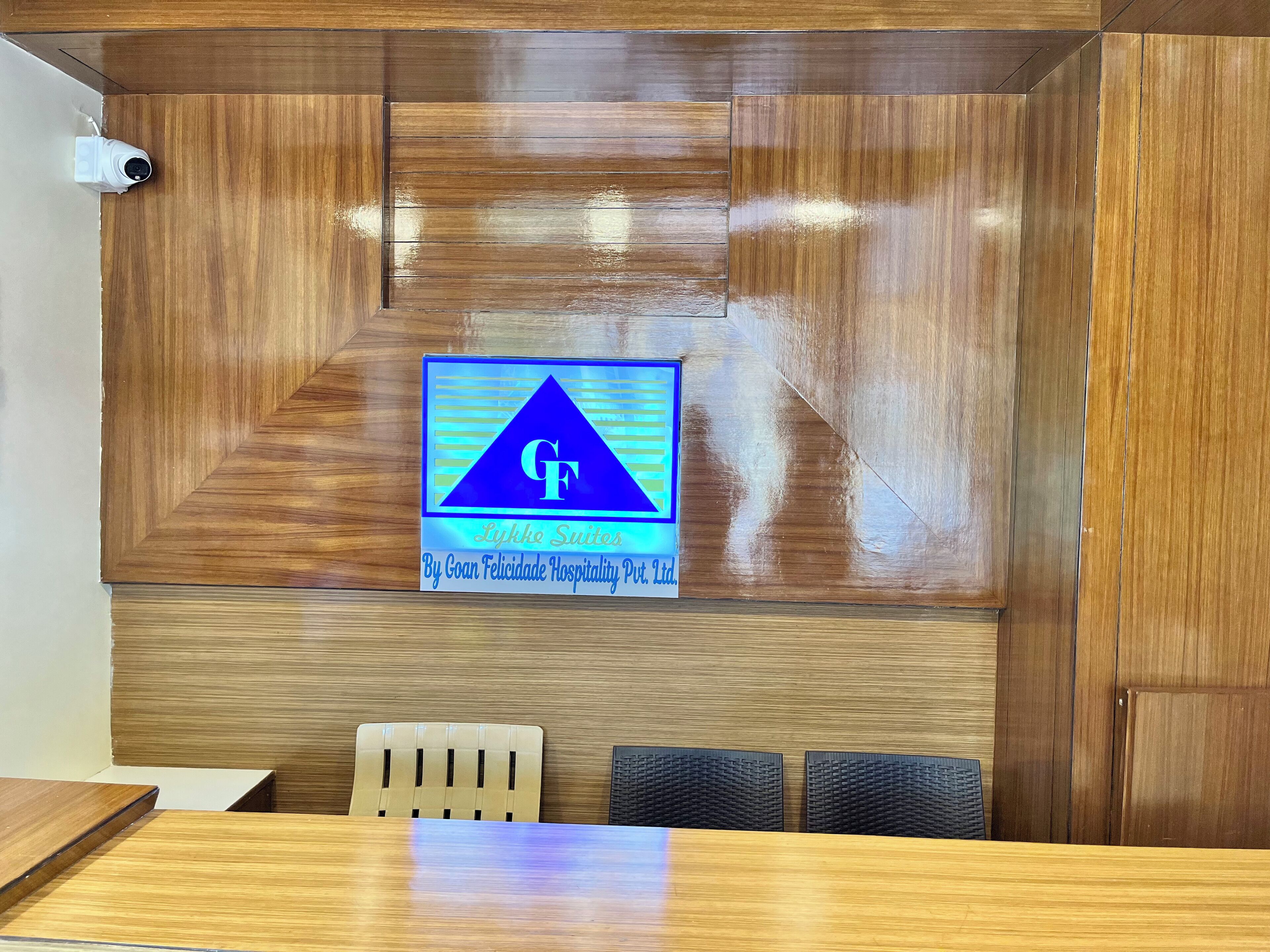 A reception area with a wooden panel wall, a logo with 'GF' and 'Lykkesuites' text, and a reception desk with chairs.