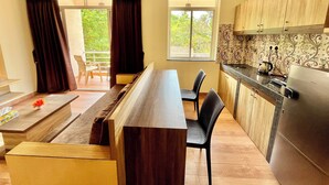 Una cocina moderna con armarios de madera, una zona de comedor con un banco y sillas, y vistas a zonas verdes al exterior.