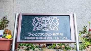 A signboard with a crest and text indicating 'Lions Mansion' in Japanese, located at '1-28, 1st Lane, 1st Block, Naka Ward, Nagoya City, Aichi Prefecture'.