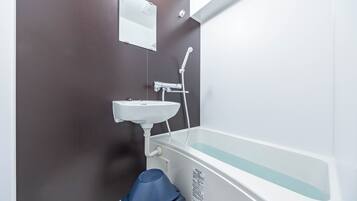 A bathroom with a white bathtub, a sink, and a blue stool.